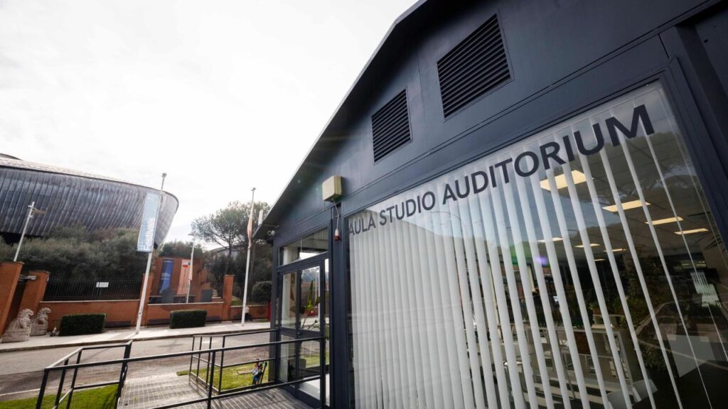 Ingresso dell'Aula Studio Auditorium con rampa accessibile in primo piano. Sullo sfondo, l'Auditorium Parco della Musica Ennio Morricone.
