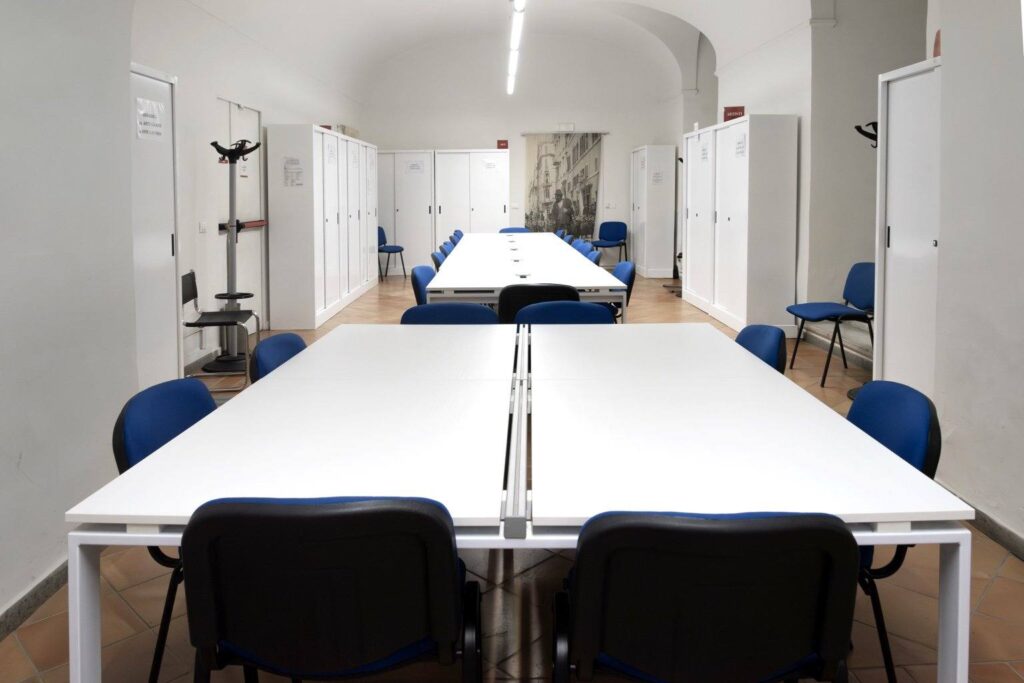 Tavoli condivisi con sedie blu nell’aula studio del Museo di Roma
