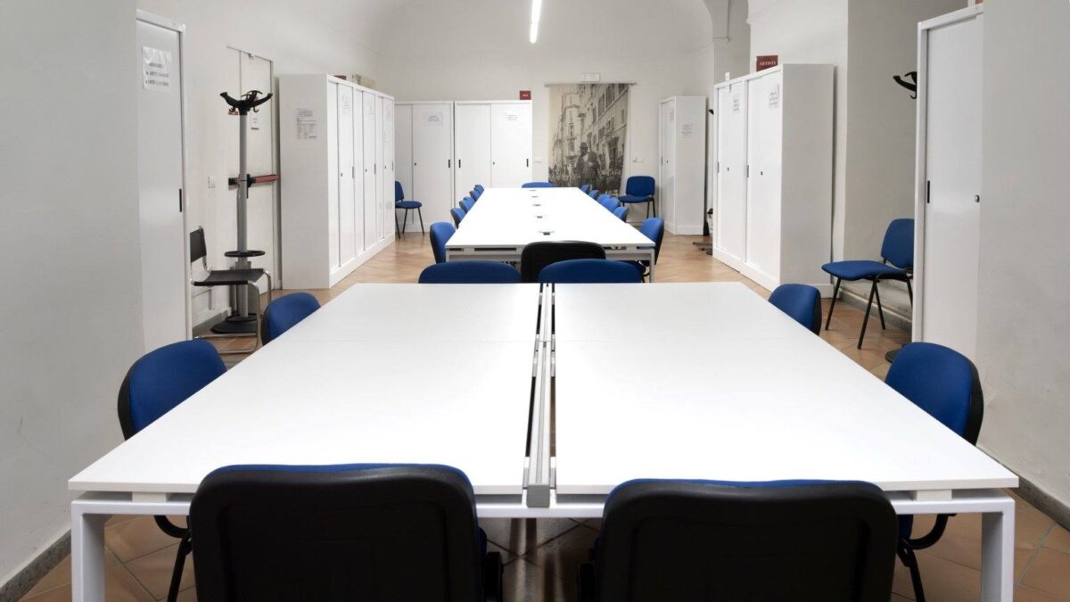 Tavoli condivisi con sedie blu nell’aula studio del Museo di Roma