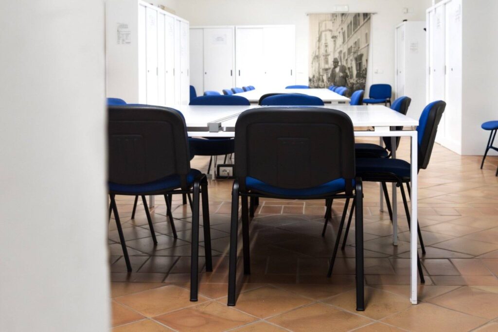 Aula studio con tavoli bianchi e sedie blu al Museo di Roma